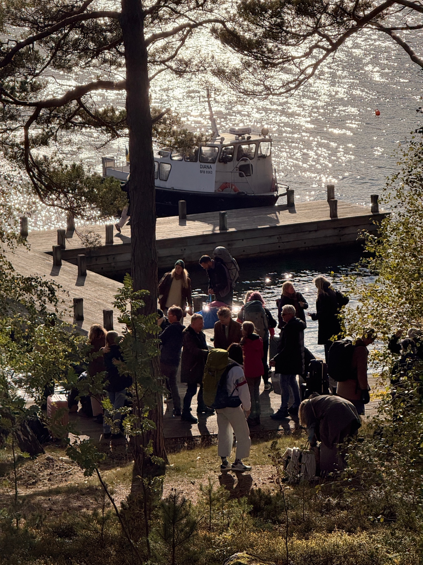 Participants arriving at the Ekskäret jetty by boat, backlit by sunlight on the water