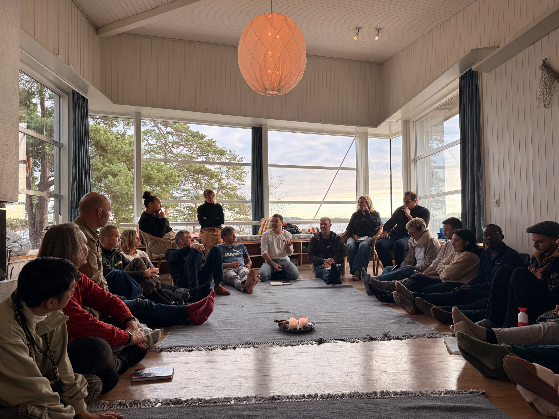 A circle of participants seated on the floor around a candle in the main hall